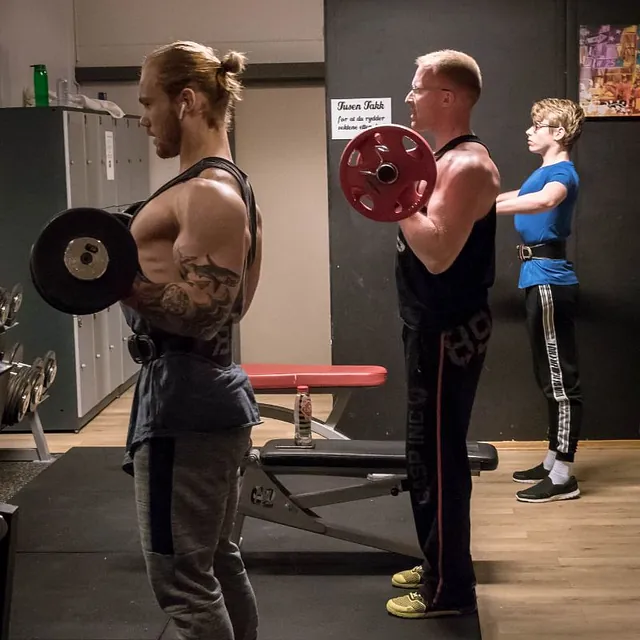 3 personer står og løfter vekter