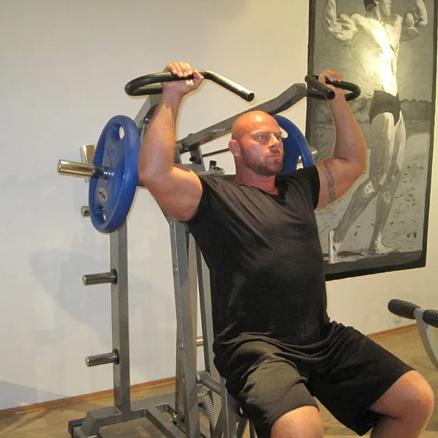 Mann sitter i treningsapparat og trener